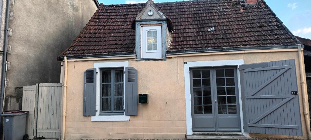 une maison avec des portes grises et un toit brun dans l'établissement La Berthenoux cottage, à La Berthenoux