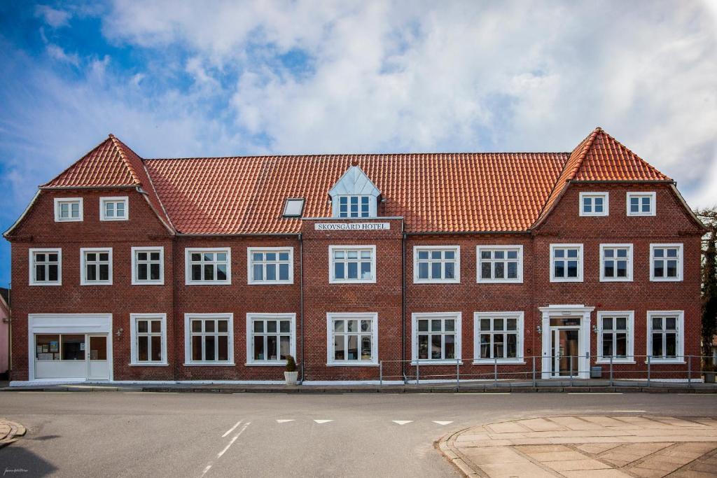 a large red brick building with white windows at Skovsgård Hotel in Brovst