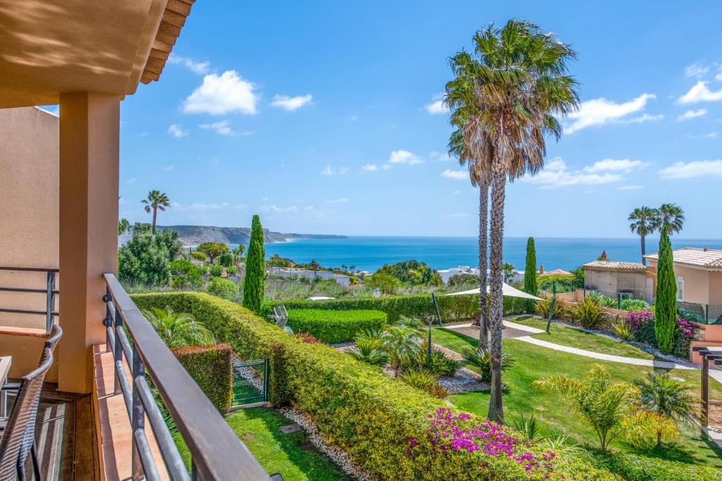 a balcony with a view of the ocean and palm trees at Mar da Luz Resort in Luz