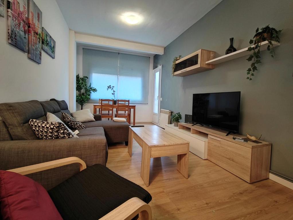 a living room with a couch and a flat screen tv at LG DownTown Sabadell Apartment in Sabadell