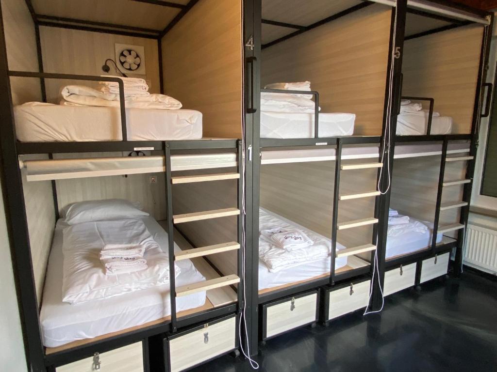 a room with three bunk beds with white sheets at Capsule Hostel by StayStay in Nürnberg