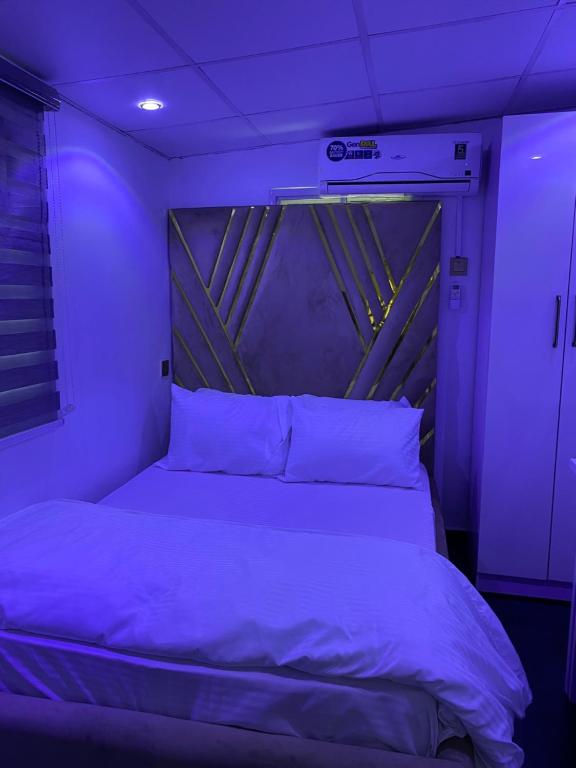 a bedroom with a bed in a purple light at HOUSE 27 HABITAT in Lagos