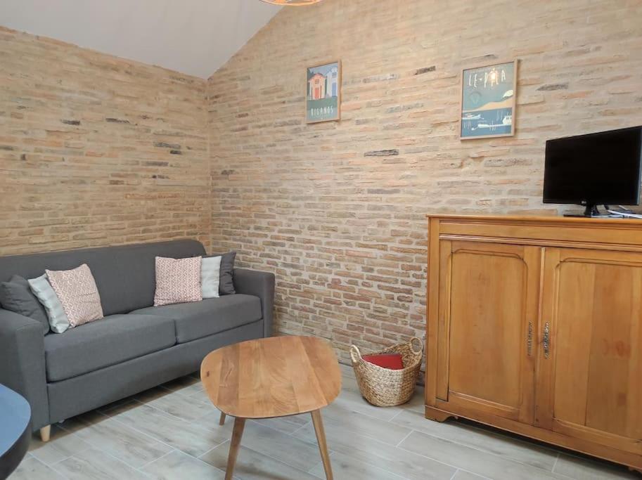 - un salon avec un canapé et une télévision dans l'établissement Studio de charme indépendant, à Belin-Beliet