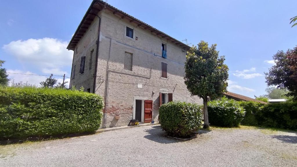 un vecchio edificio in pietra con un albero di fronte di Outlander Cottage - Family B&B a Bentivoglio