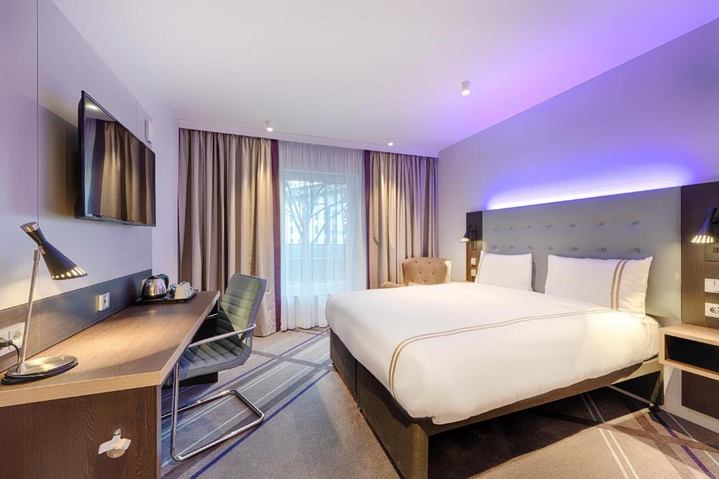 ein Hotelzimmer mit einem großen Bett und einem Schreibtisch in der Unterkunft Premier Inn Düsseldorf City Friedrichstadt in Düsseldorf