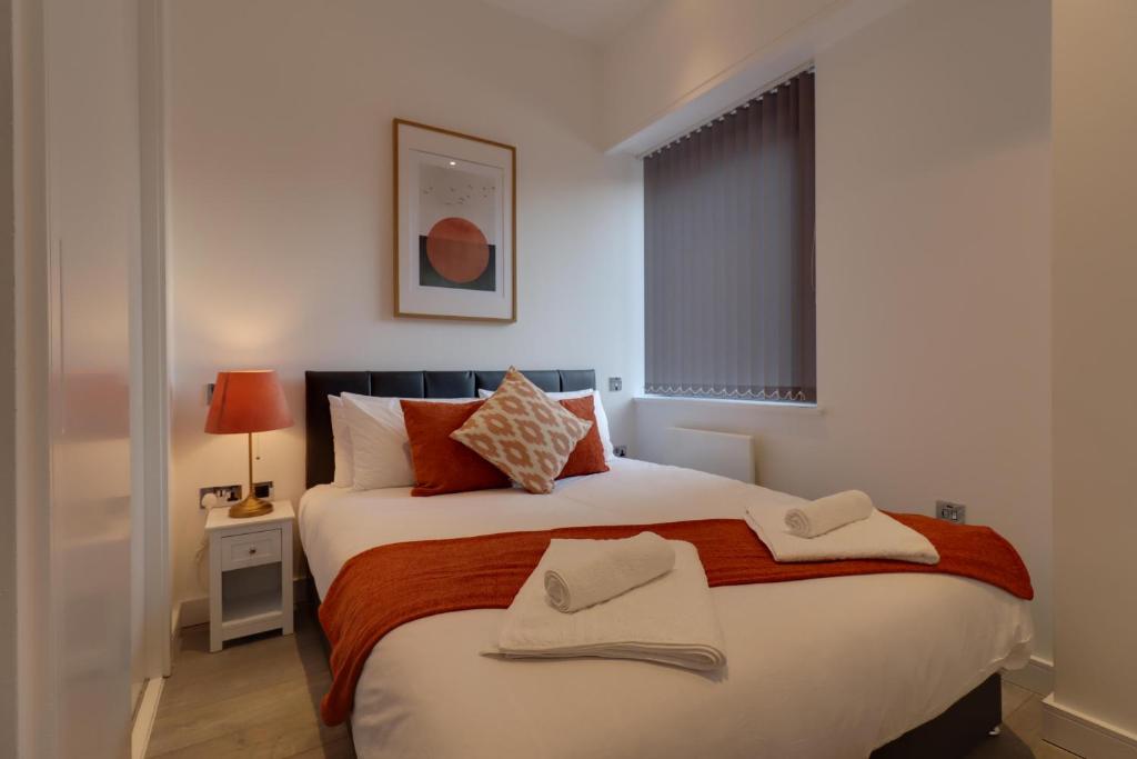 a bedroom with a large bed with two towels on it at La Casa Suites Slough in Slough