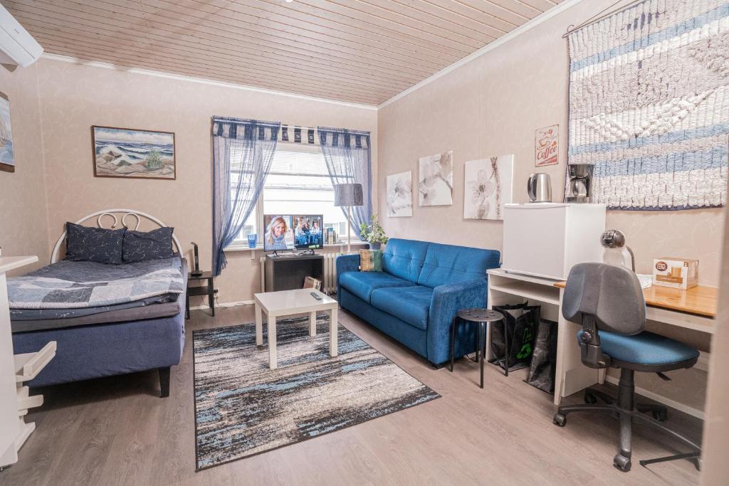 - une chambre avec un canapé bleu, un lit et un bureau dans l'établissement Käytännöllinen huoneisto Pietarsaaressa, à Pietarsaari