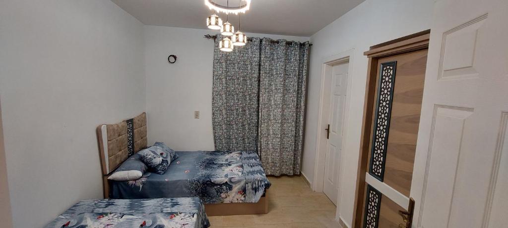 1 dormitorio con 2 camas y lámpara de araña en Chalet in Blumar El Dome for families only, en Ain Sokhna
