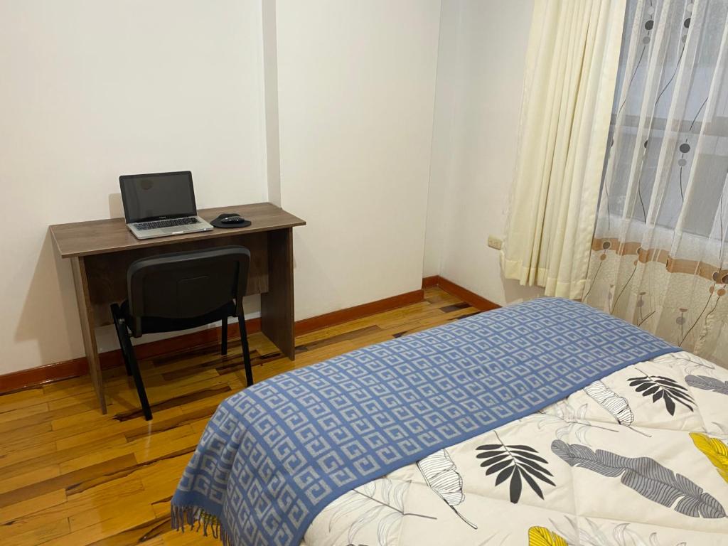 een slaapkamer met een bed en een bureau met een laptop bij Hogarcito in Cuzco