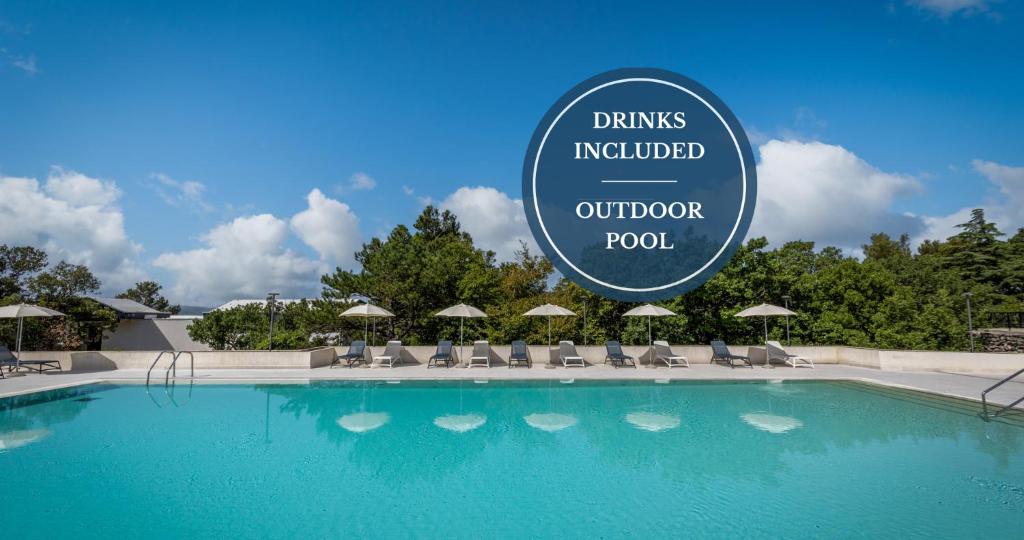 a pool at the drius updated outdoor pool with chairs and umbrellas at Holiday Resort Ad Turres in Crikvenica