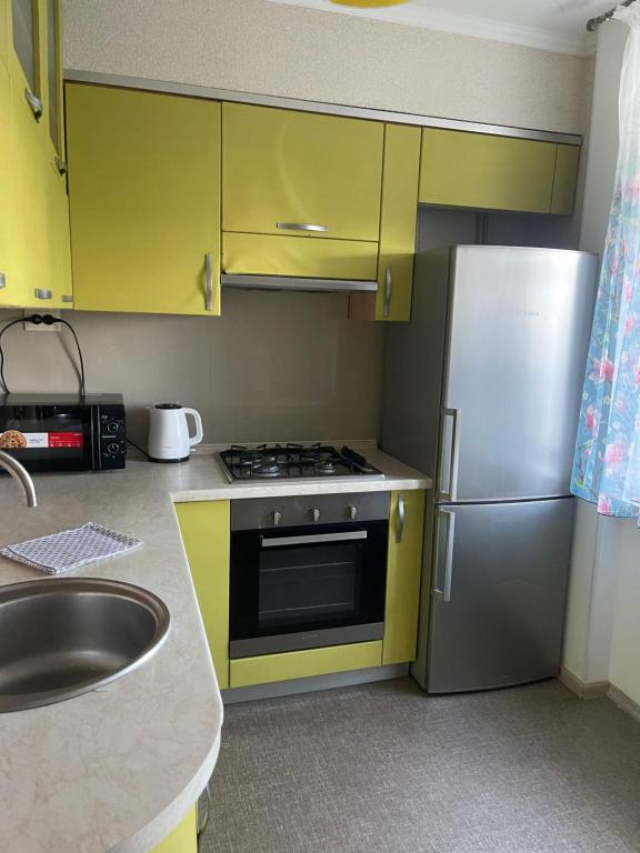 a kitchen with yellow cabinets and a stainless steel refrigerator at Квартира з видом на Дніпро in Cherkasy