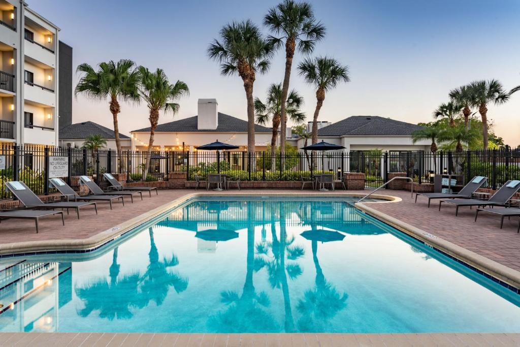 a swimming pool with chairs and palm trees at Courtyard Tampa Westshore/Airport in Tampa