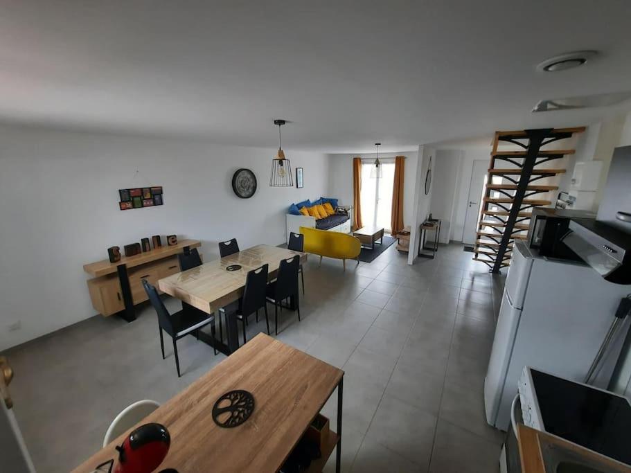 uma cozinha e sala de estar com mesa e cadeiras em gîte Mouettes et Chouettes em Saint-Hilaire-Petitville