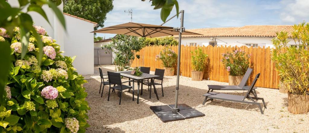 een patio met een tafel en stoelen en een parasol bij villa Hortense in Saint-Martin-de-Ré