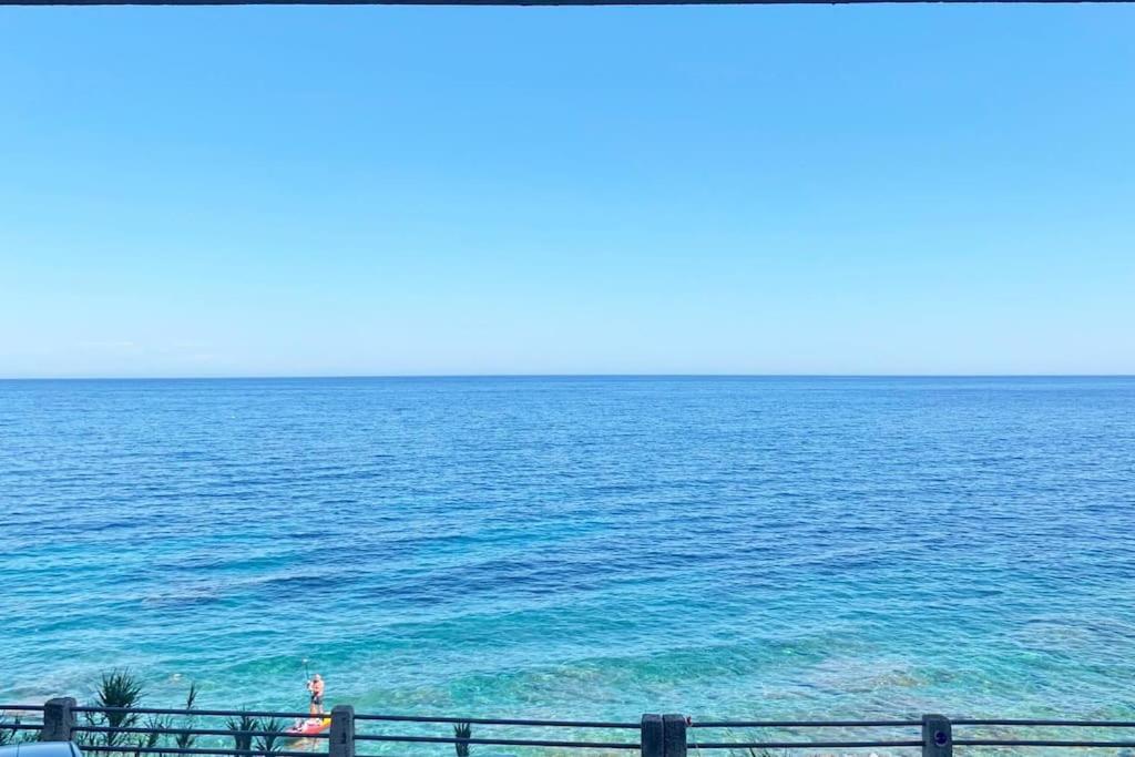 uma vista para o oceano a partir de uma praia com uma cerca em Appartement en bord de mer em Pietranera