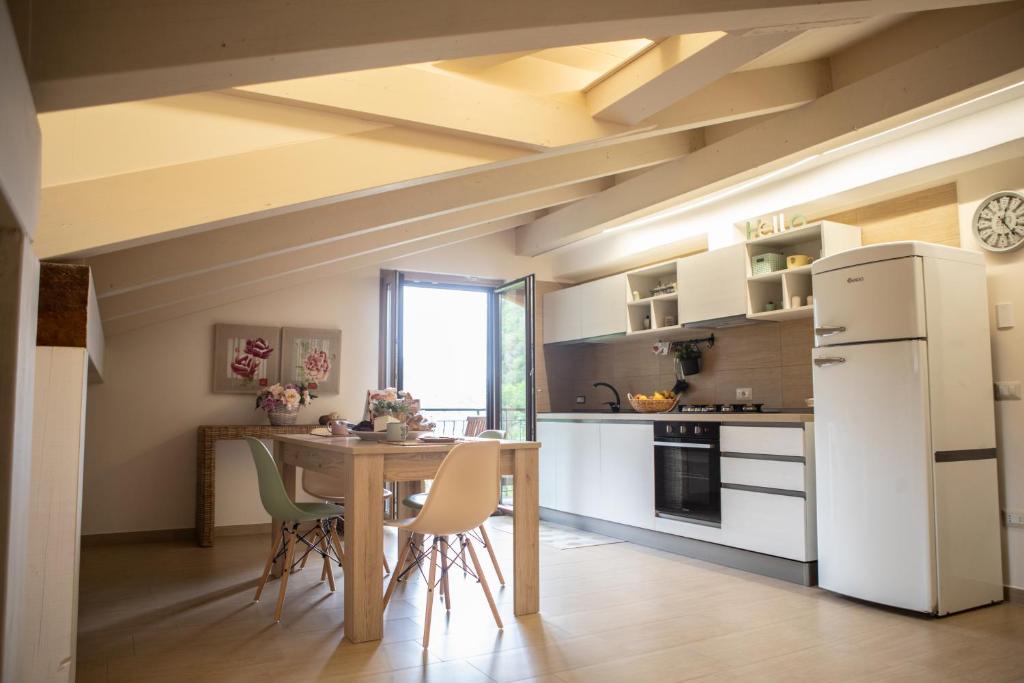 una cocina con electrodomésticos blancos, mesa y sillas en Sofis Home, en Pimonte