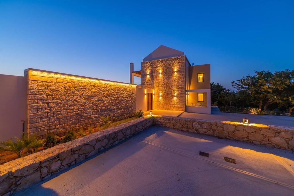 une maison avec un mur en pierre et des lumières sur elle dans l'établissement Vita Brevis - Premium Villa 15km From The Beach, à Vederoi
