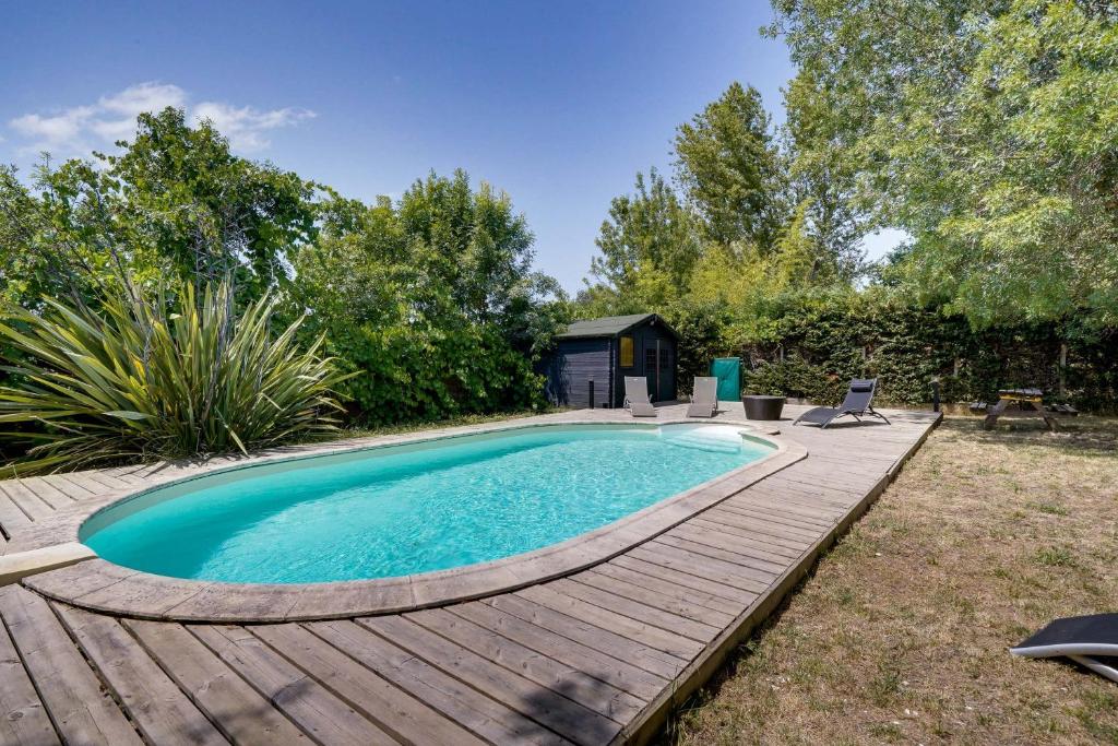une piscine avec une terrasse en bois et une maison dans l'établissement La Villa Kudeta - Belle maison avec piscine, à Bouliac