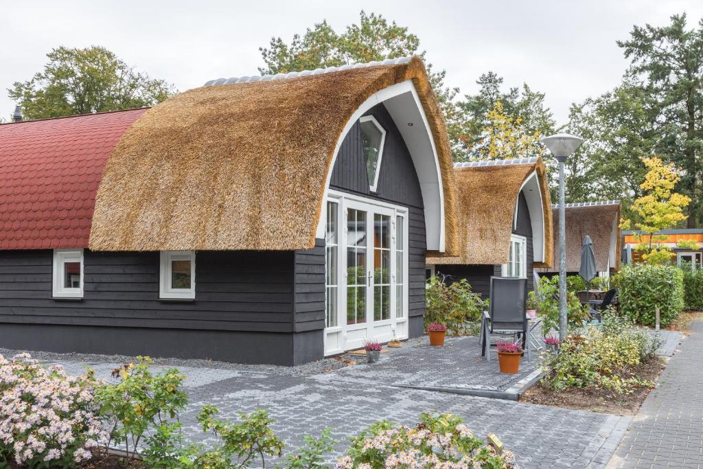 een gebouw met een rieten dak en een tuin bij Residence de Eese in De Bult