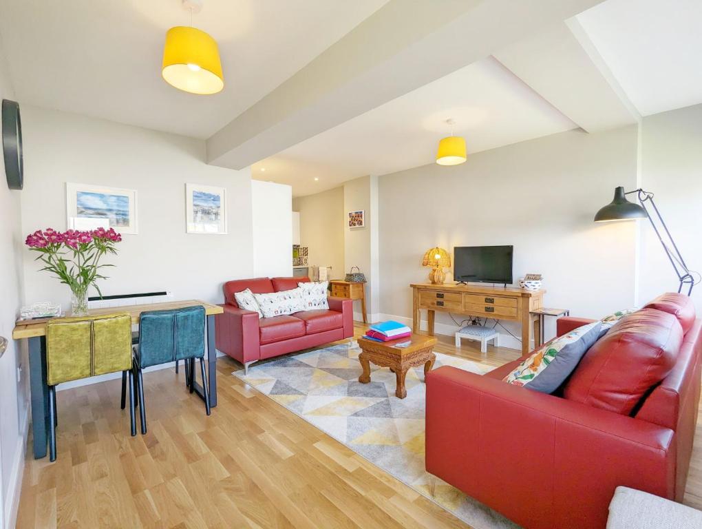 a living room with a red couch and a table at Pebblestone in East Wittering