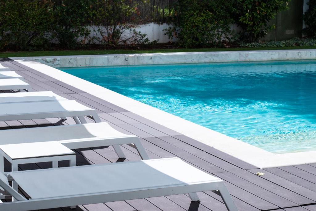 een zwembad met witte ligstoelen ernaast bij Evora Olive Hotel in Évora
