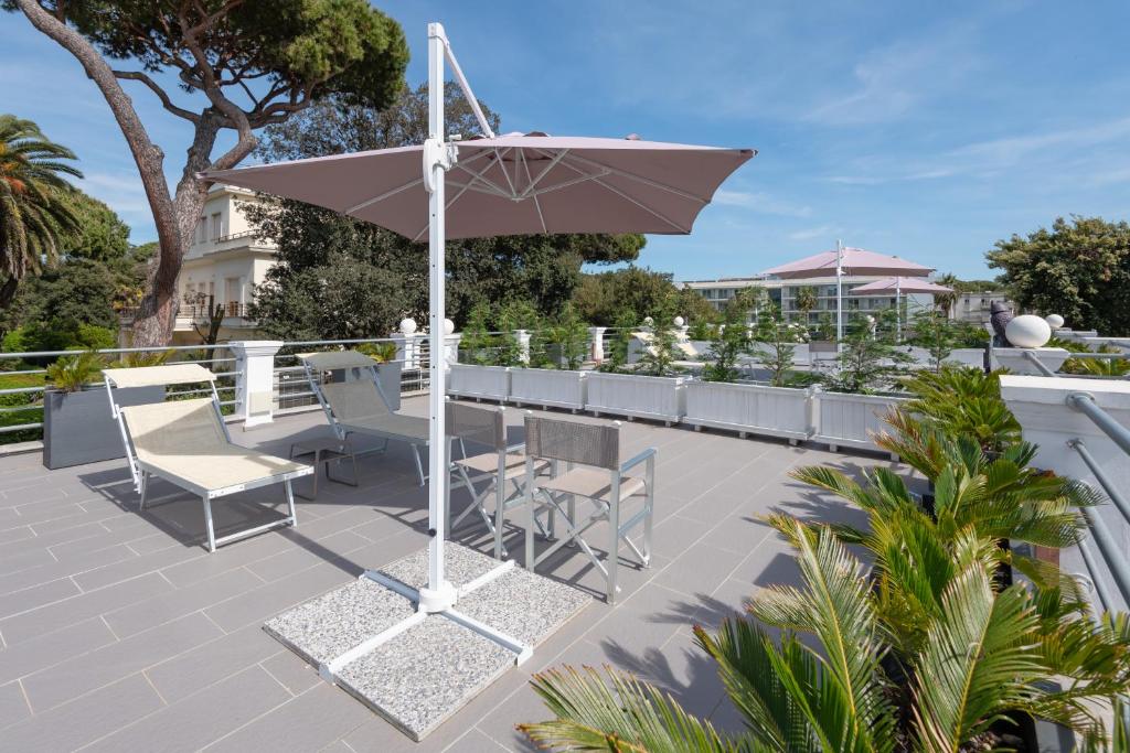 a patio with a table and chairs and an umbrella at Lido Luxury Villas in Lido di Camaiore