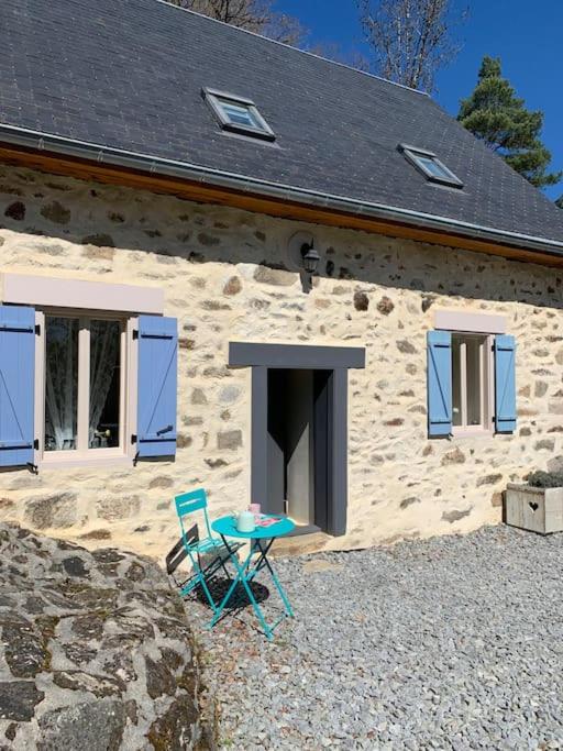 une maison en pierre avec une table et des chaises devant elle dans l'établissement Gîte Maison du Trottoir, Sussac, à Sussac