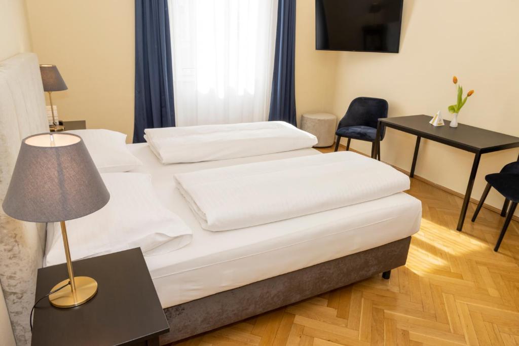 2 łóżka w pokoju z lampką i biurkiem w obiekcie Hotel Mariahilf w Grazu