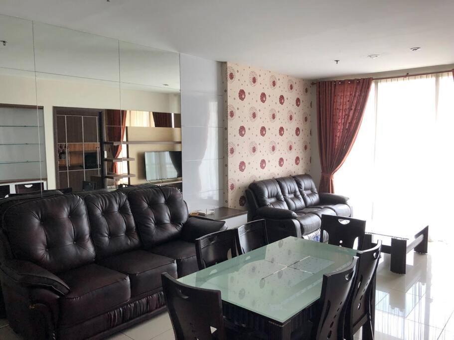 ein Wohnzimmer mit einem Ledersofa und einem Tisch in der Unterkunft Central Park Apt. 3 Bedroom (42nd Floor - Alaina) in Jakarta