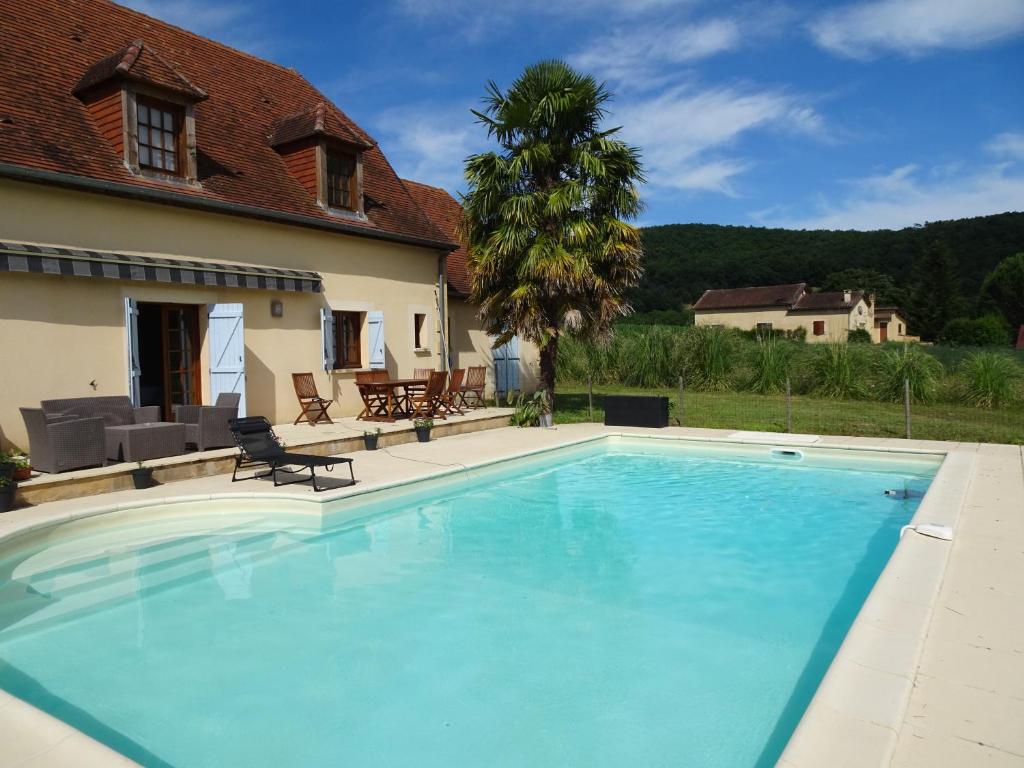 une grande piscine en face d'une maison dans l'établissement Charmante Maison à Vézac au cœur des 5 Châteaux en Dordogne, à Vézac