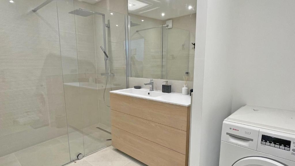 a bathroom with a sink and a shower and a washing machine at Miremer in Sainte-Maxime