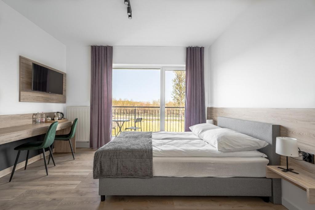 a bedroom with a bed and a desk and a balcony at Morski Piasek in Grzybowo