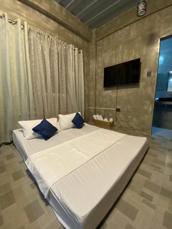 uma grande cama branca com almofadas azuis num quarto em Hai Inn em Dumaguete