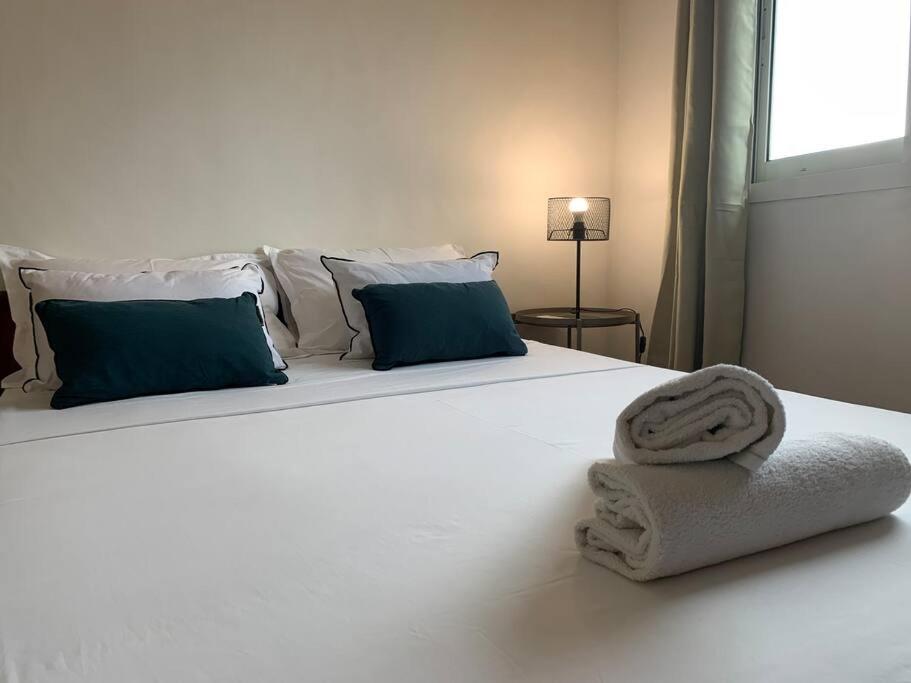 a white bed with blue pillows and towels on it at studio cocoon perche 119 Mdz in Mamoudzou