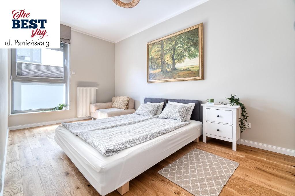 a white bedroom with a bed and a chair at The Best Stay Central Apartment Gdansk in Gdańsk