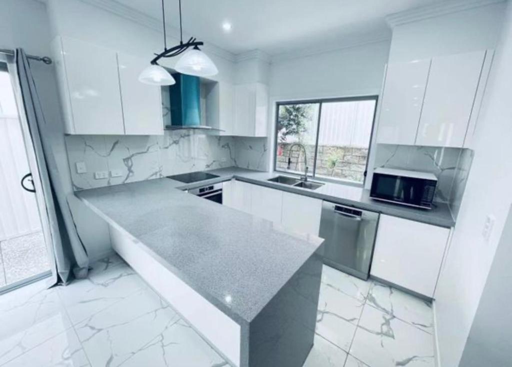 una cucina con armadi bianchi e piano di lavoro di A5U3 Hostel a Gold Coast