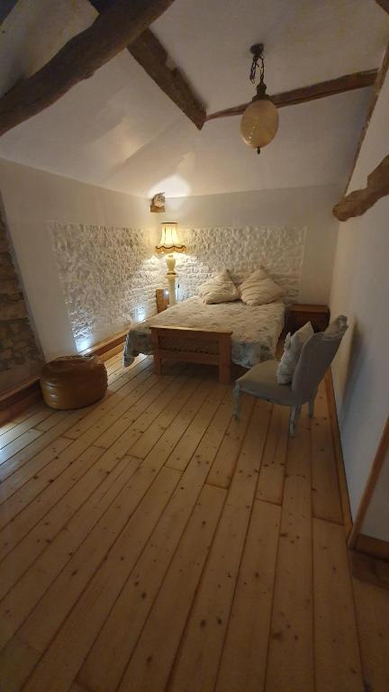 a bedroom with a bed and a chair in a room at Chateau Mano in Mairé-lʼEveseault