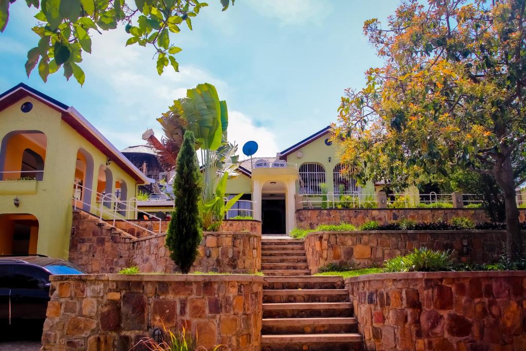 een huis met een stenen muur en een trap bij Emerald Villa in Kigali