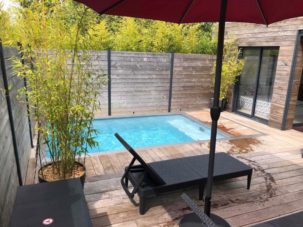 - une piscine avec un parasol, une table et une chaise dans l'établissement Loft privatisé avec spa XXL et piscine chauffée, à Bruz