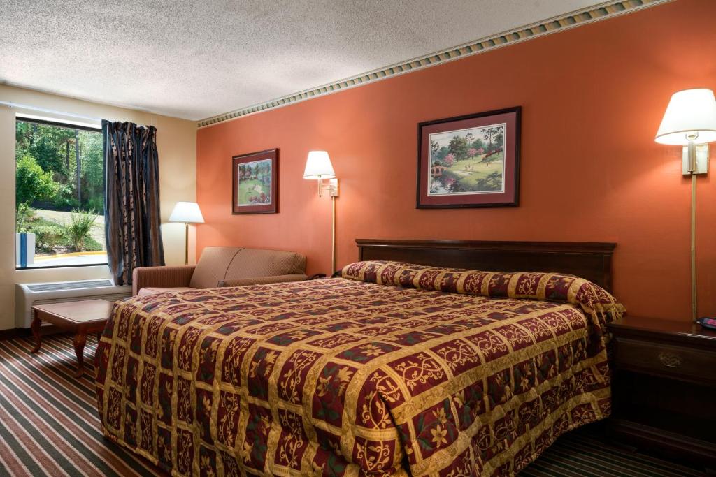 a hotel room with a bed and a chair and a window at Knights Inn Aiken in Aiken
