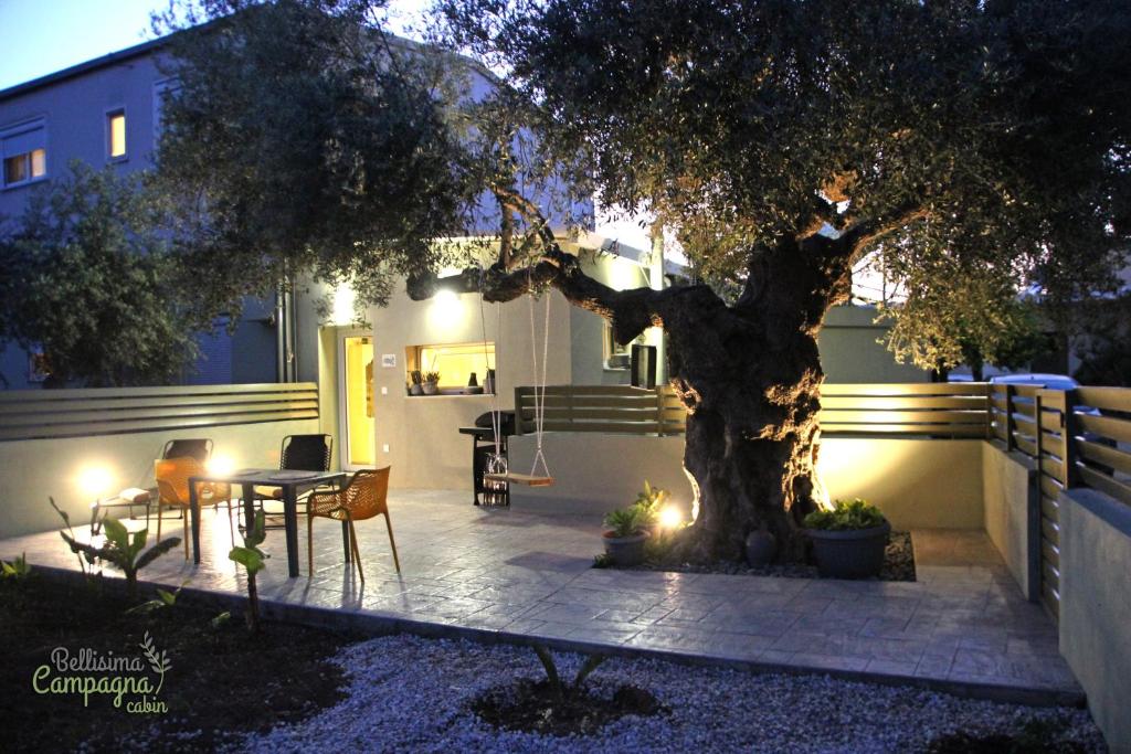 un patio con un árbol, una mesa y sillas en Bellisima Campagna Cabin Pelekapina - Chania Crete en La Canea
