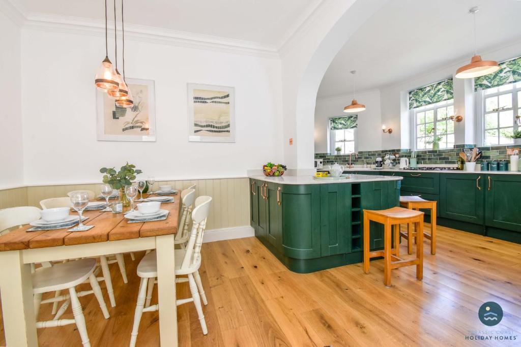 a kitchen with green cabinets and a wooden table at The Old Chapel - Exclusive Retreat in Weymouth