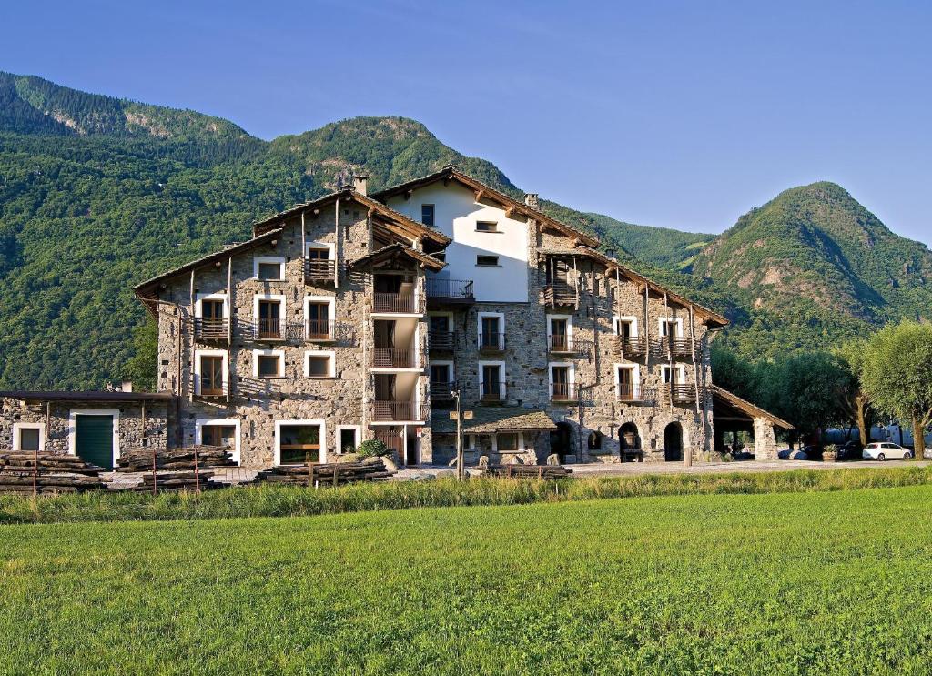 a large stone building with mountains in the background at La Brace in Forcola