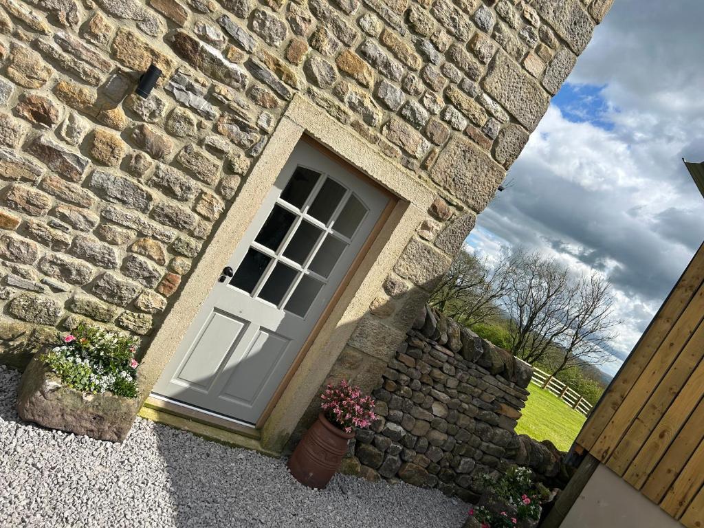 a stone house with a door and a stone wall at Tosside Fold Farm Cottage in Skipton