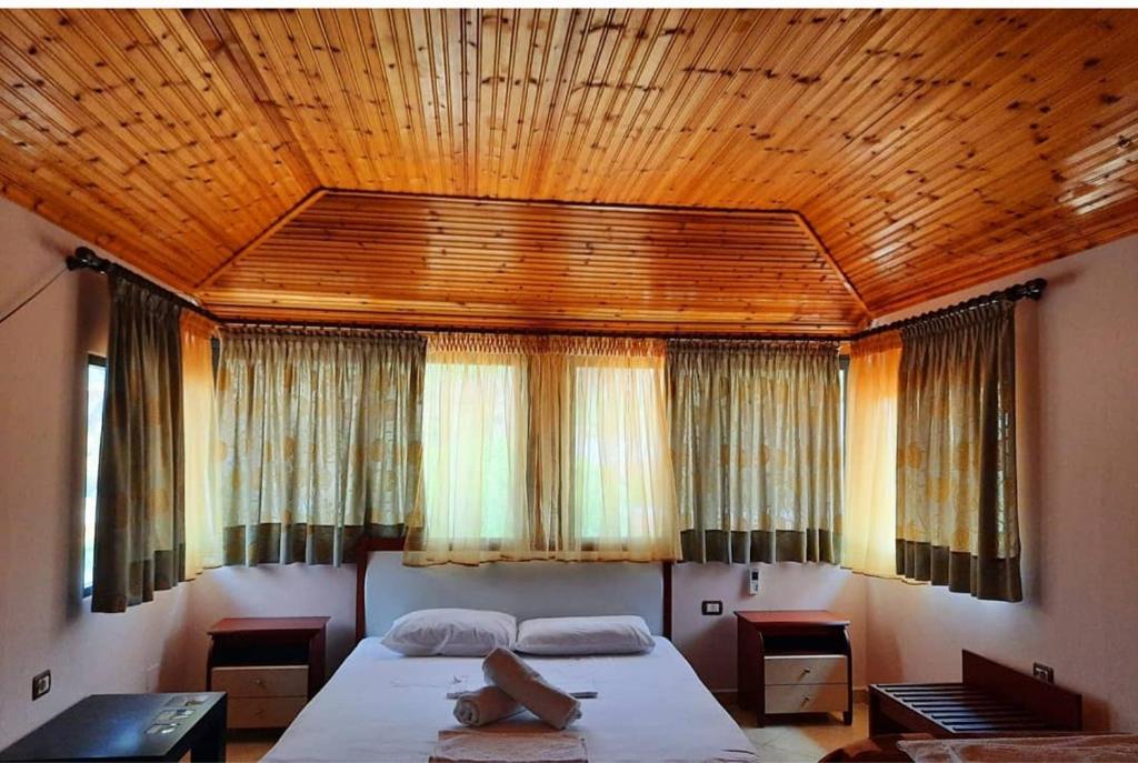 Hotel Marsil في Tepelenë: غرفة نوم بسرير كبير بسقف خشبي