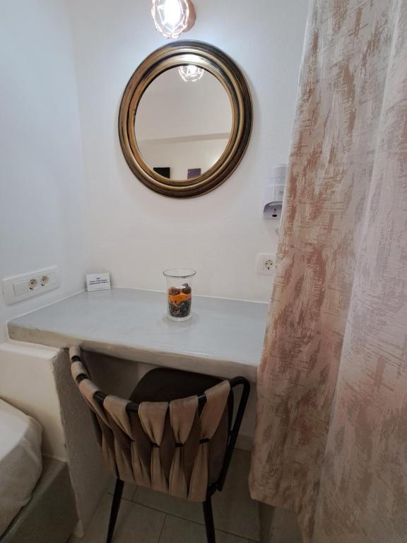 a mirror and a chair in a bathroom at Studios Irineos in Perissa