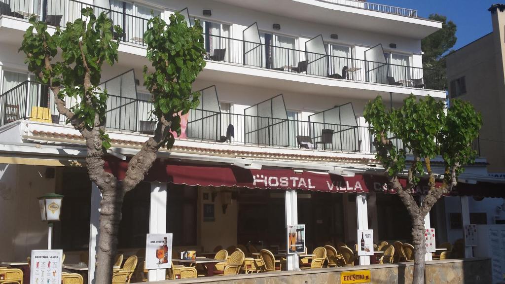 een hotel met tafels en stoelen voor een gebouw bij Hostal Villa Catí in Paguera