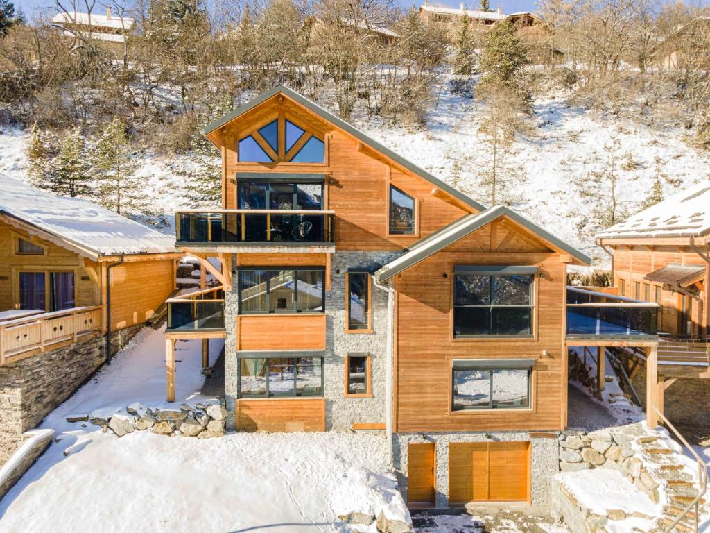 una casa di tronchi in inverno con neve sul terreno di Chalet Lumière - LaGodille Prestige - 16 personnes - Pra Loup a Uvernet