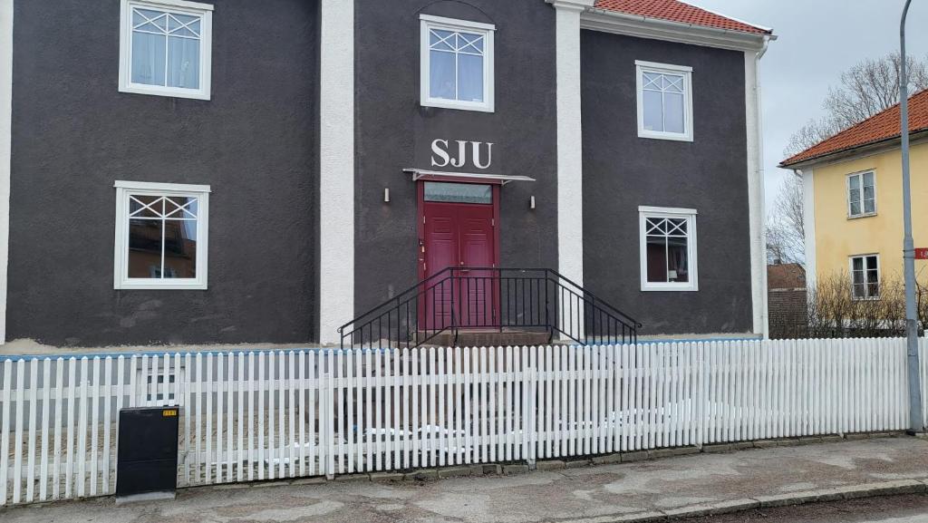uma casa preta com uma porta vermelha e uma cerca branca em Centralt i Mariestad em Mariestad