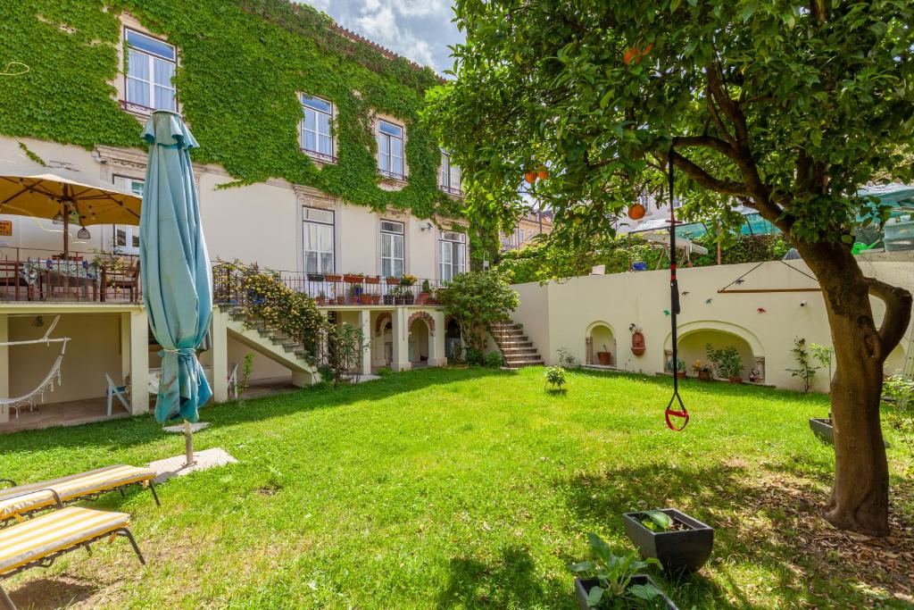 a building with a yard with a umbrella and a tree at Sky Accommodations family Studios and Suites in Coimbra